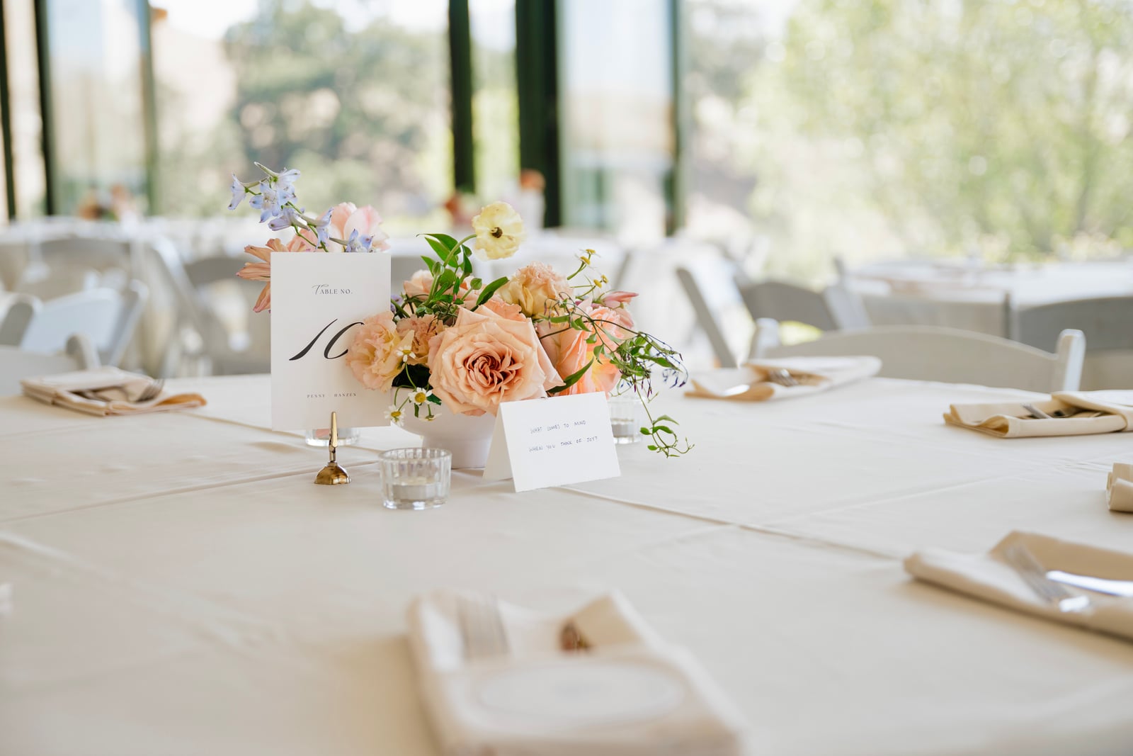 Peach floral centerpiece with a table number at a reception