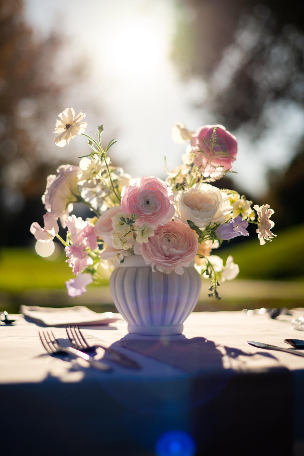 Blush, ivory, and lavender centerpiece in a fluted white vase