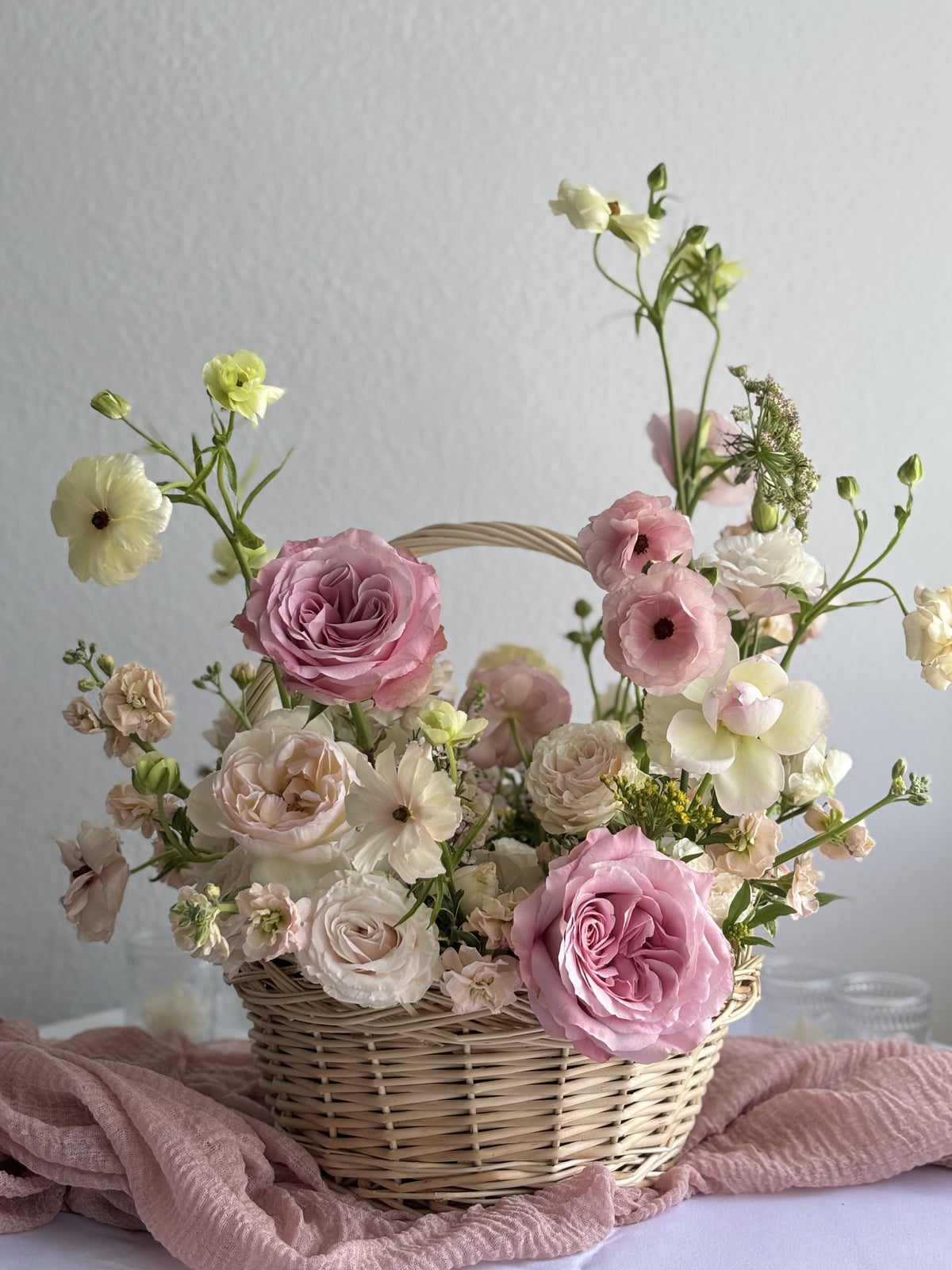 Pink and ivory flowers arranged in a basket