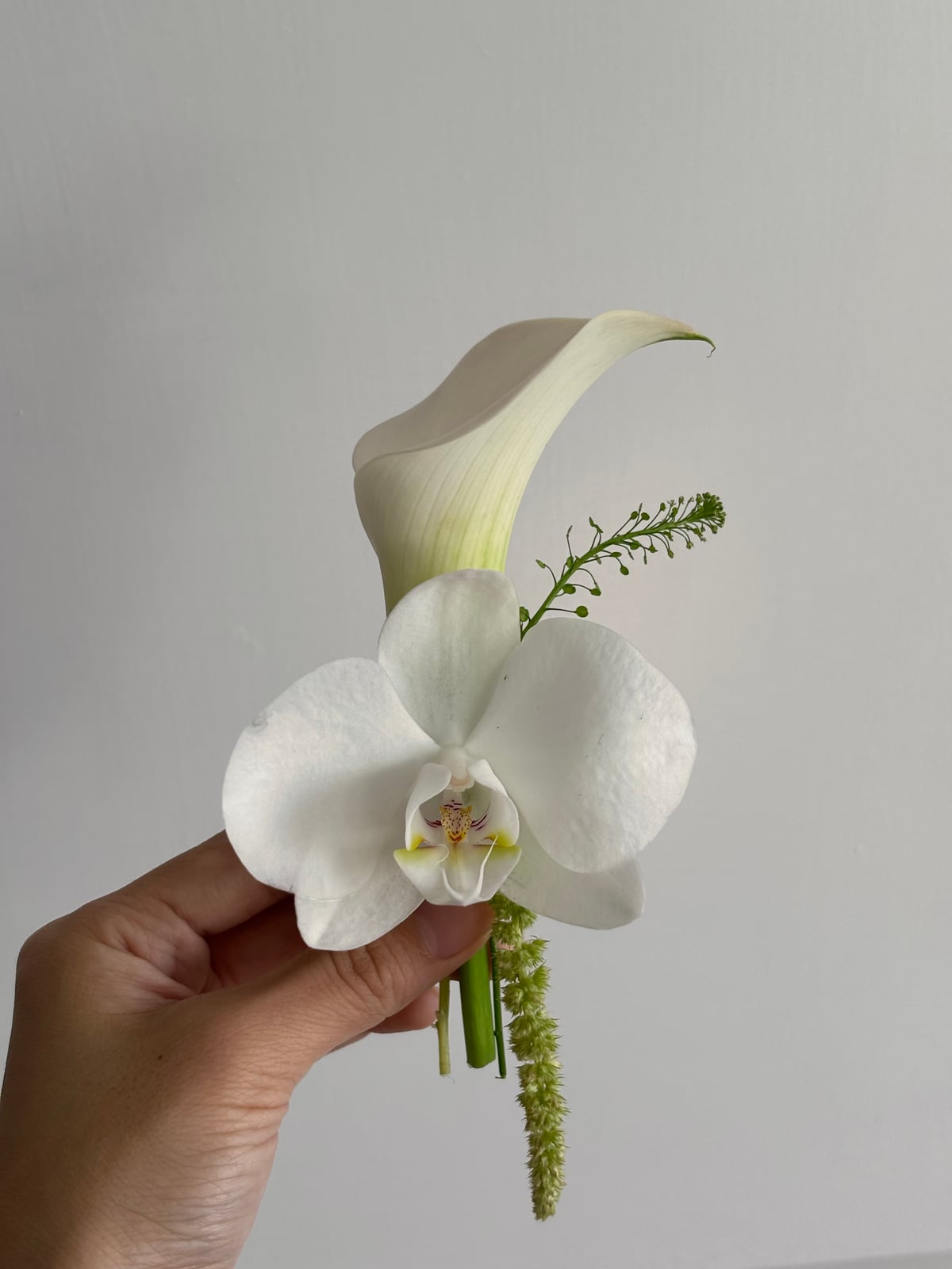 White calla lily boutonniere held in hand