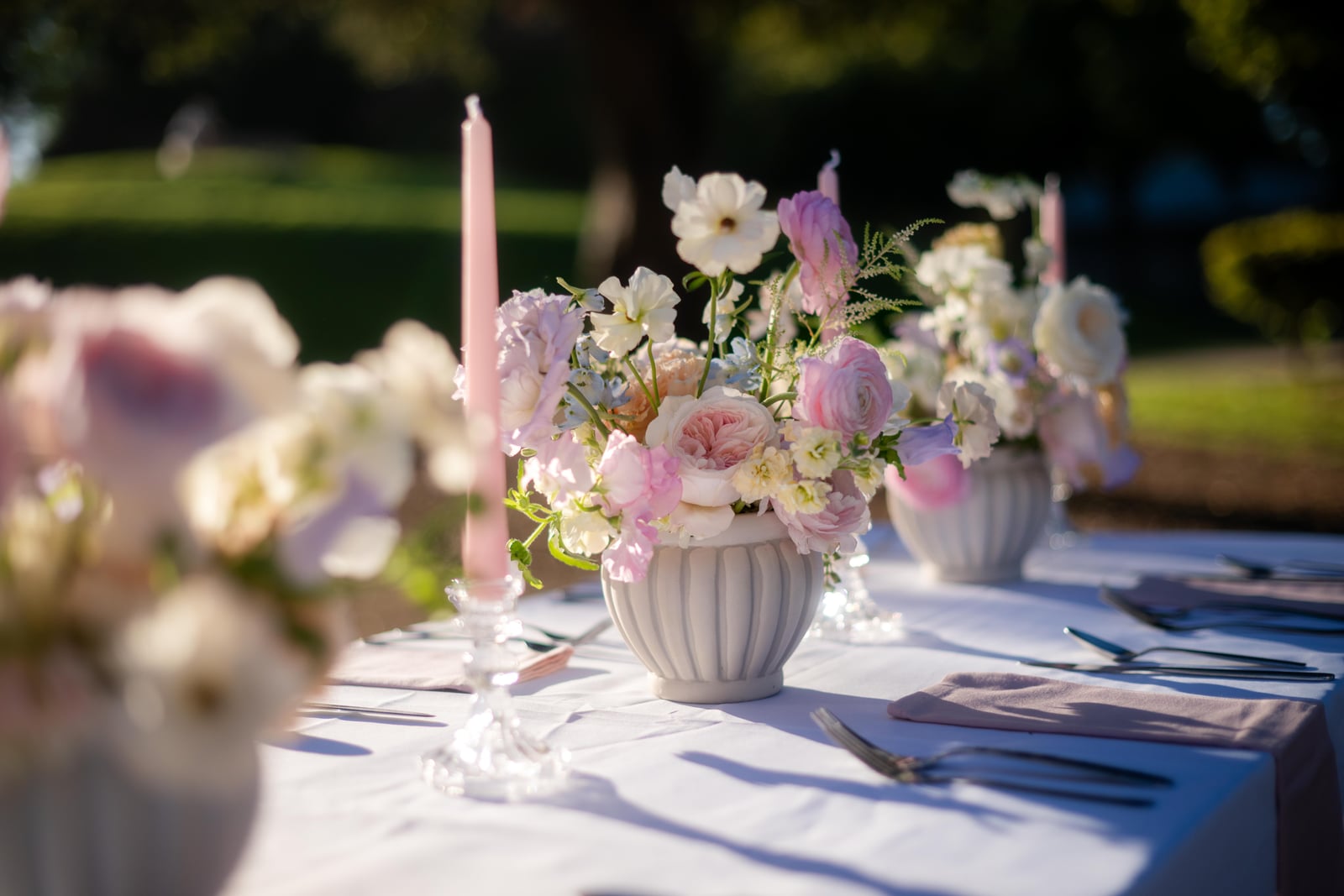 Pastel floral centerpiece and pink candle on an outdoor reception table