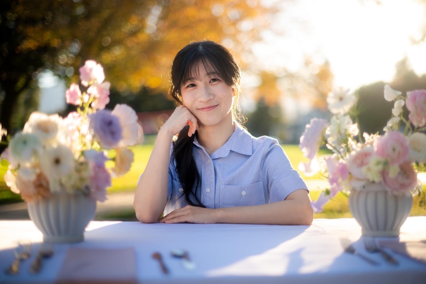 Shirley seated between floral arrangements