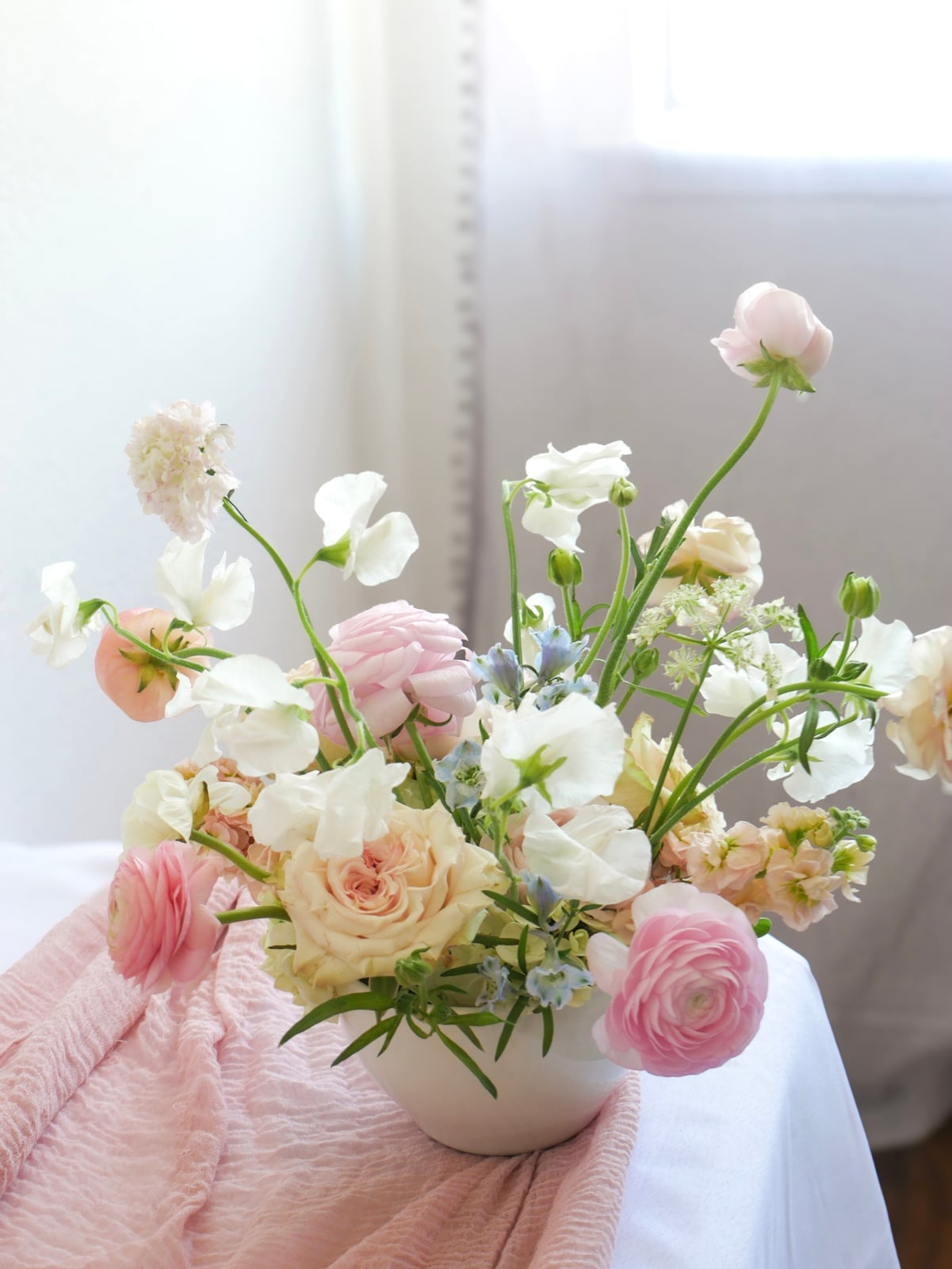 Pastel garden flowers arranged in a white vase