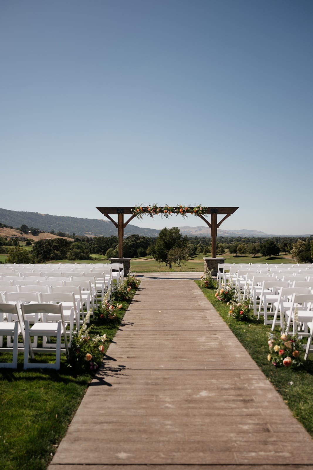 Outdoor wedding ceremony aisle with a flower-adorned arch